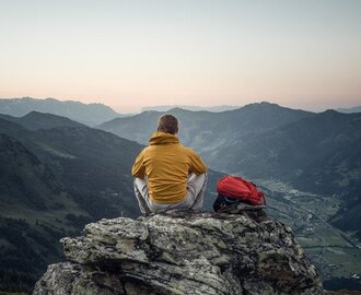 A man sits on a rock and watches the sunset over the mountains | © Gasteinertal Tourismus GmbH - moodley
