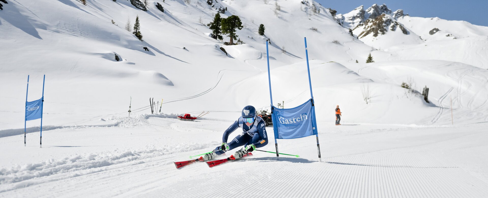 A ski racer carves through a slalom gate in deep turn on sunny day with powder snow. | © Gasteinertal Tourismus GmbH, Marktl Photograhpy