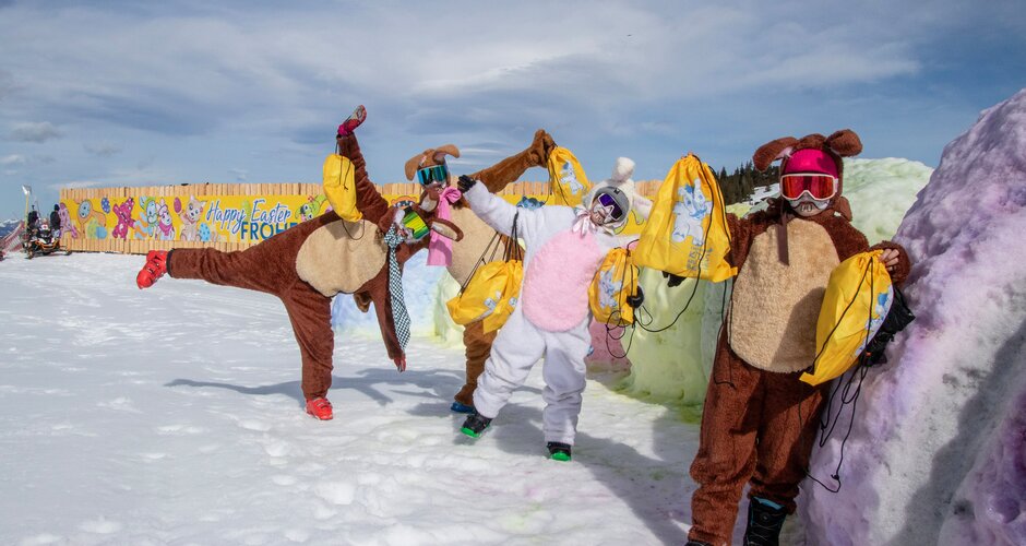 Four people in bunny costumes holding yellow goodie bags on colorfully dyed snow in ski resort | © Shuttleberg