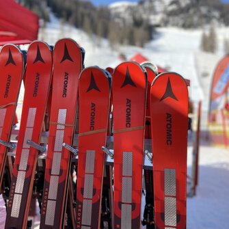 Red Atomic ski pairs leaning against a ski rack
