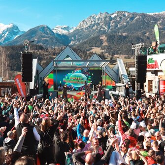 Singer DJ Ötzi stands on stage and sings while the crowd in front of the stage sings along with raised arms. | © Hauser Kaibling