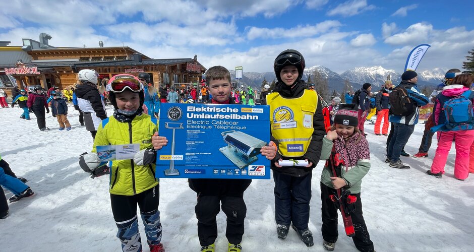 Four kids show their prizes at the Easter egg hunt in the snow in front of the Rauchkuchl at Hauser Kaibling | © Hauser Kaibling