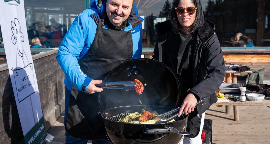 Johann Lafer and a woman grill together on a kettle grill at the Schaf-Alm. | © Mario Egger