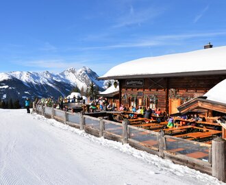 Terrace of a ski hut located directly on the piste and with a view of a snow-covered mountain range