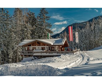 Ski hut next to a piste and behind it are snow-covered trees