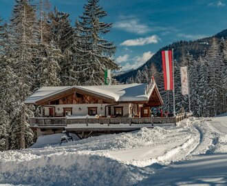 Ski hut next to a piste and behind it are snow-covered trees