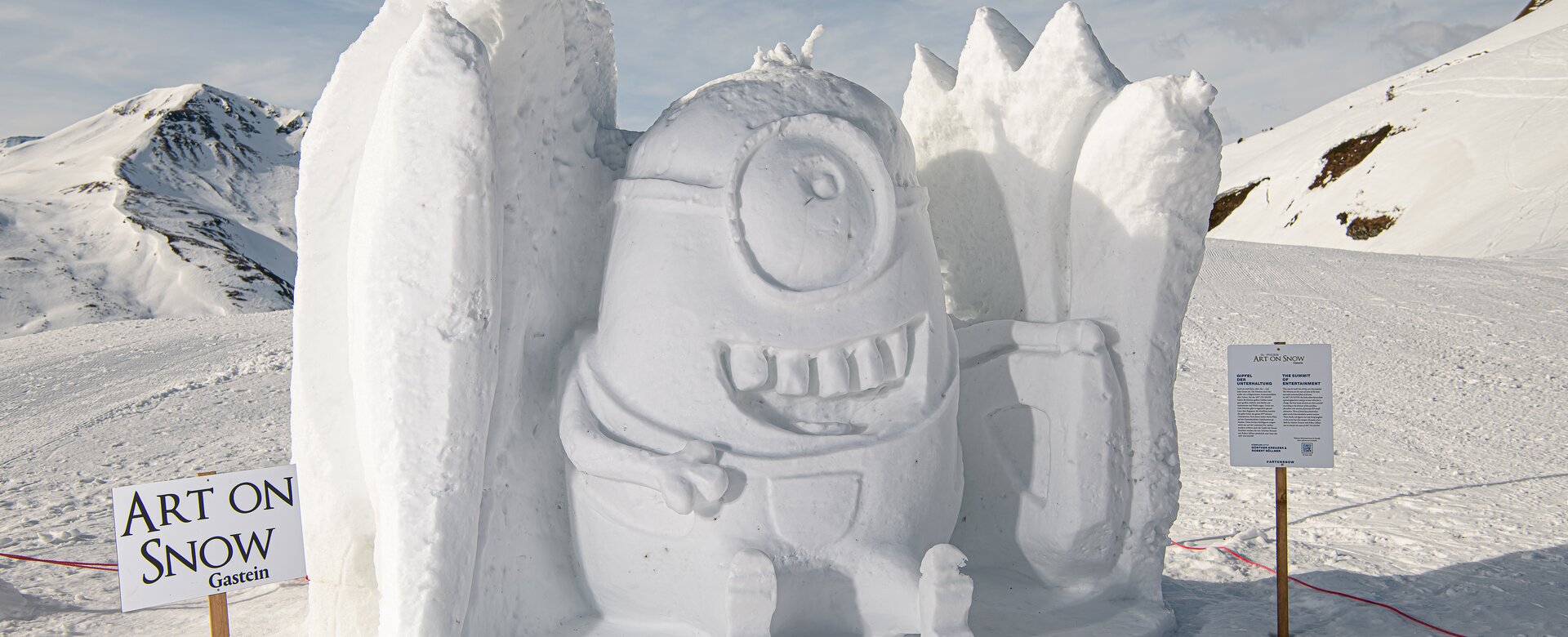 Große Schneeskulptur eines grinsenden Minions mit Details auf verschneitem Plateau in Gastein.