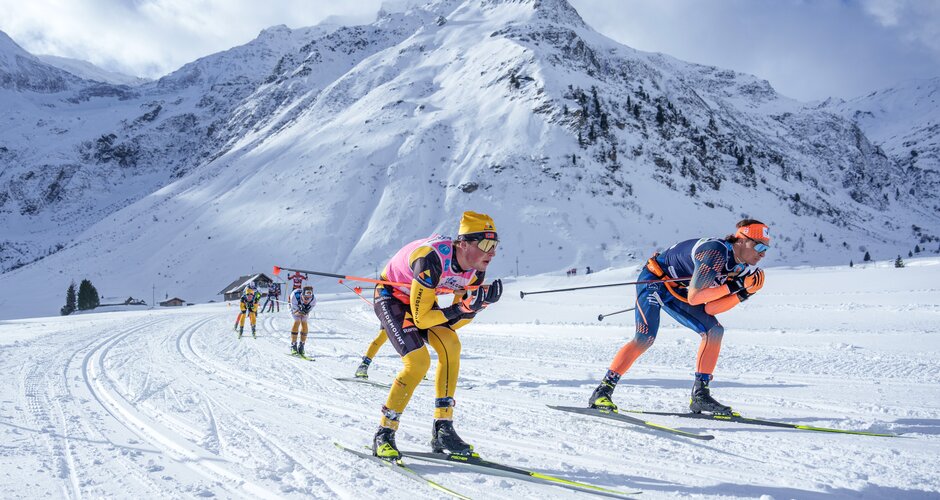 Two skiers lead a race in sunshine through a snow-covered mountain landscape at Gastein Classics. | © Gasteinertal Tourismus, Christoph Oberschneider