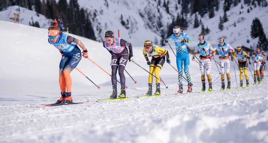 Group of female skiers climbs in racing formation through sunlit snowy mountains at Gastein Classics. | © Gasteinertal Tourismus, Christoph Oberschneider
