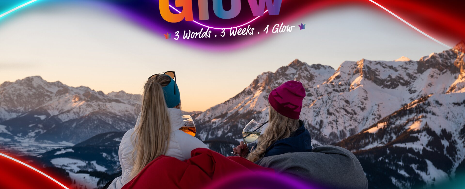 Two women with drinks sit facing snowy Alps at sunset, March Glow graphic overlay above