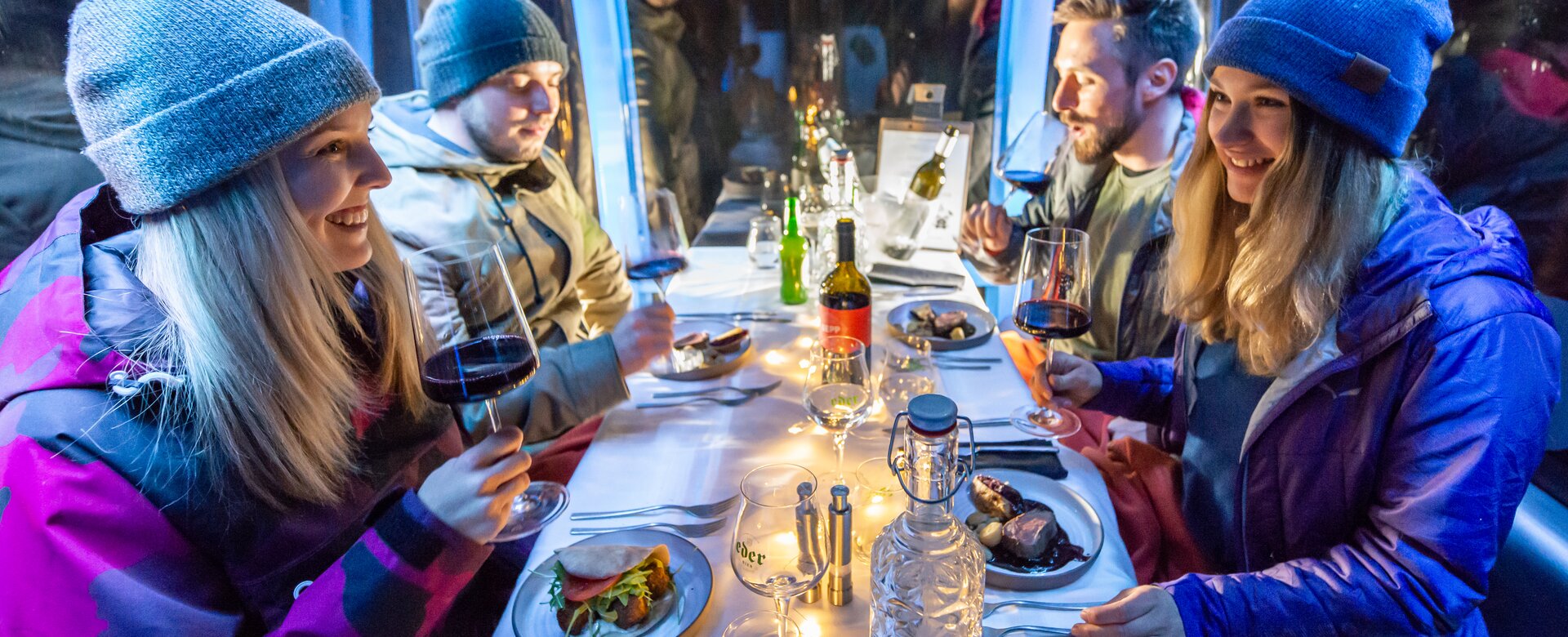 Zwei Paare sitzen in einer schön gedeckten Gondel mit Wein, Hauptspeise und lachen sich an. | © Edith Danzer 