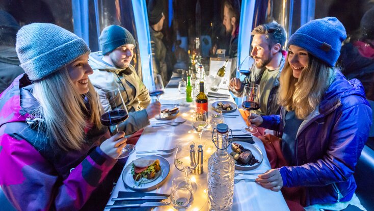 Two couples sit in a beautifully set gondola with wine, main course and laugh at each other. | © Edith Danzer 