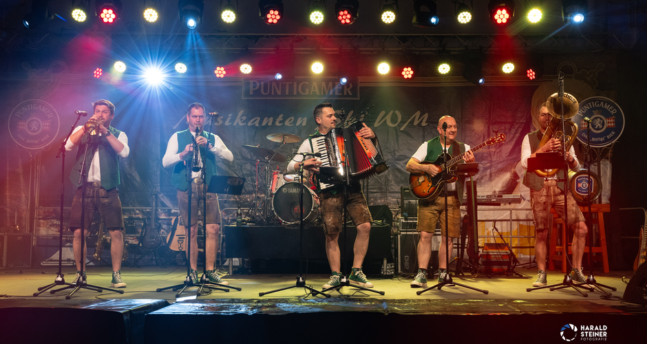 Six musicians in traditional outfits perform on a lit stage at Musikanten Ski World Cup in Schladming | © Harald Steiner