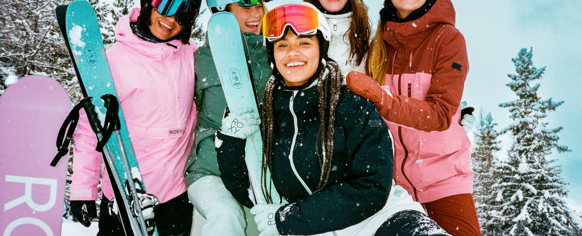 Fünf junge Damen haben Skibekleidung an und stehen zusammen mit ihren Skiern im Schnee und lachen | © QParks