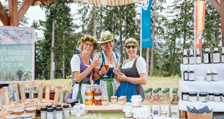 Three women in dirndls with flower crowns present herbal products at the Hochkönig herb festival. | © Miriam Lottes