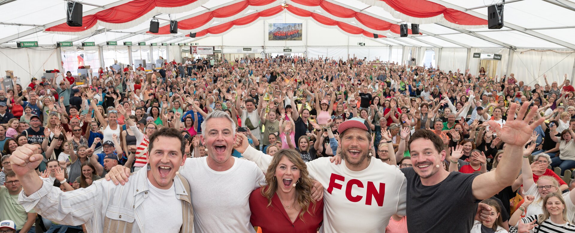 Main cast of TV series "Die Bergretter" cheerfully pose with hundreds of fans in large event tent at 2024 Fan Day in Ramsau | © Martin Huber