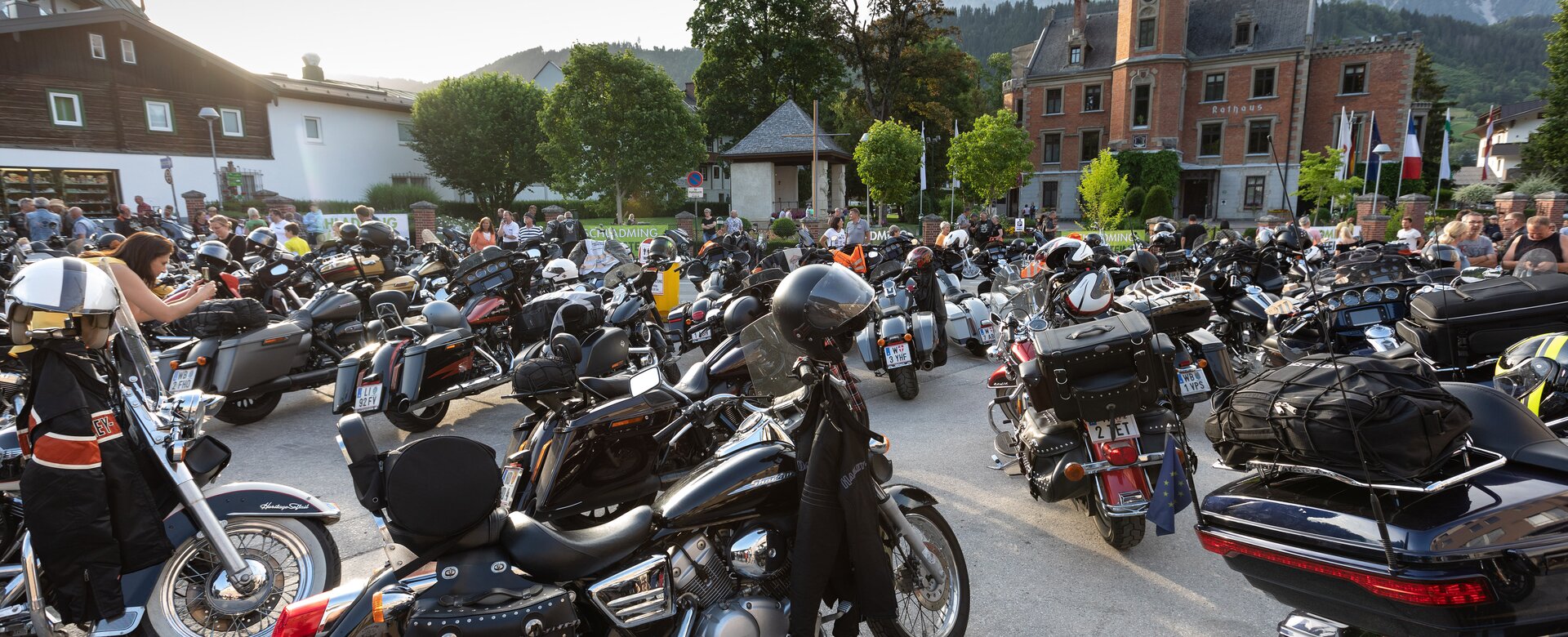 Dozens of Harley-Davidson bikes and riders gather in front of historic building during Alpine charity tour event | © Harald Steiner