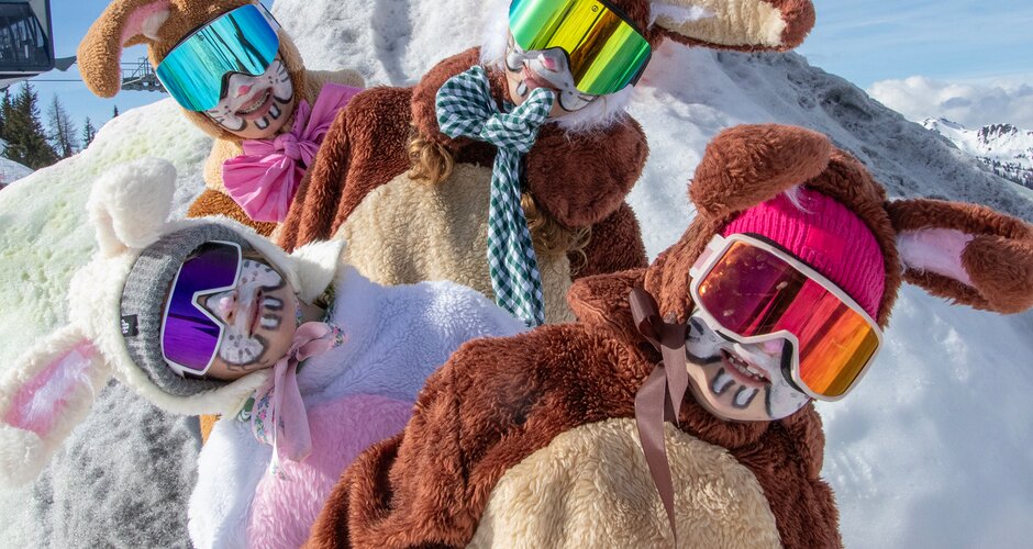 Four people in colorful bunny costumes and ski goggles posing playfully on a snowy hilltop | © Shuttleberg