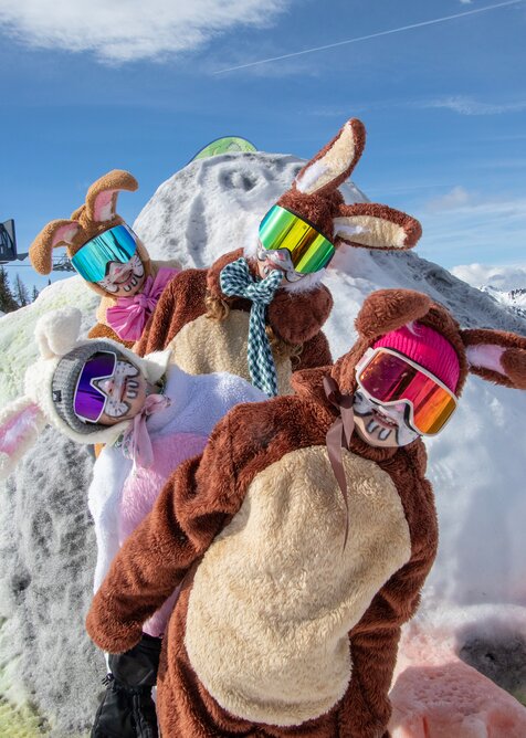 Four people in colorful bunny costumes and ski goggles posing playfully on a snowy hilltop | © Shuttleberg