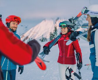 A group of skiers carrying their skis chats together – part of the Back2Ski course for returning skiers. | © Ski amadé