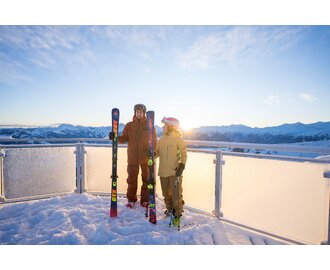 Zwei Skifahrer mit Skiern auf verschneiter Plattform bei Sonnenaufgang in Dorfgastein | © Dorfgasteiner Bergbahnen AG/Christoph Oberschneider