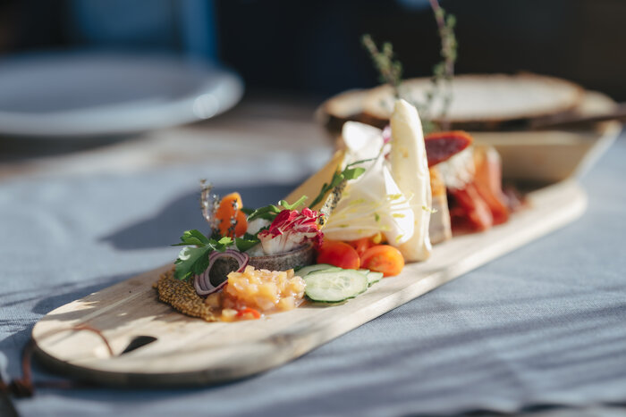 Close-up of snack board with cheese, cold cuts, tomatoes, cucumbers, herbs and mustard seeds | © Ski amadé