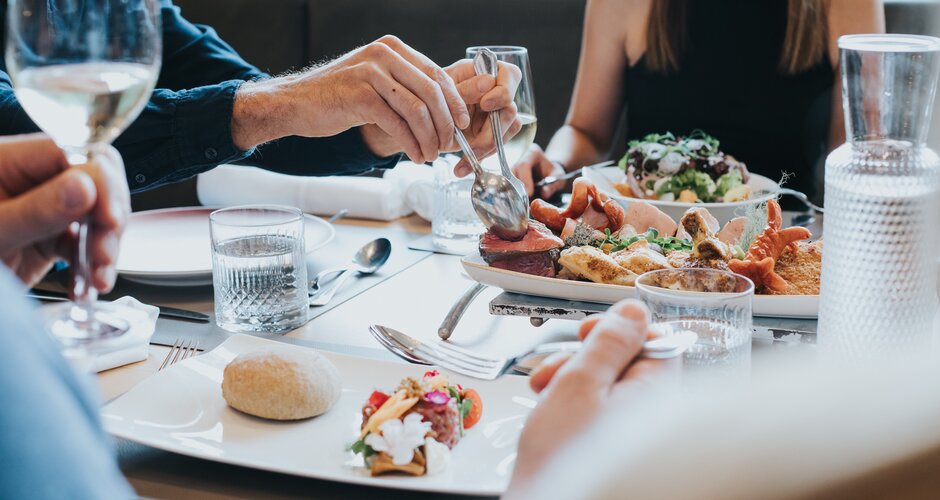People sharing a platter with meat, salad and bread in the hotel restaurant