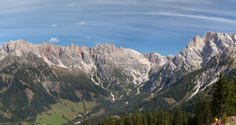 Wide view of the Steinernes Meer with autumn forest, mountain lake and fence in front, panoramic scene under clear skies.