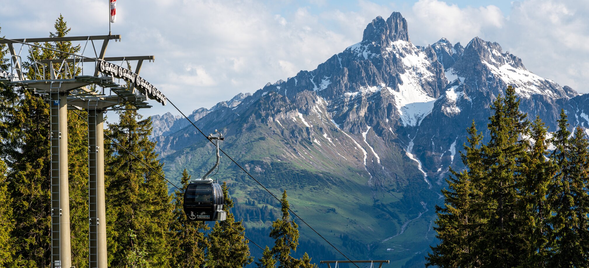Papageno gondola in front of iconic Bischofsmütze peak in Filzmoos, surrounded by meadows and conifer forest | © Coen Weesjes