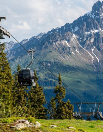 Papageno gondola in front of iconic Bischofsmütze peak in Filzmoos, surrounded by meadows and conifer forest | © Coen Weesjes