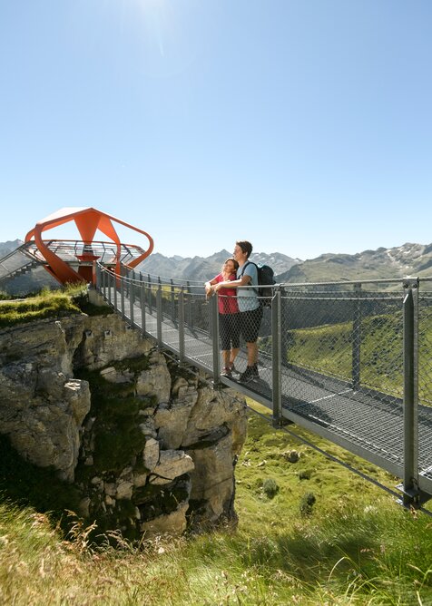 Two people enjoy the view on Stubnerkogel’s cliff trail toward Glocknerblick platform in bright sunny weather | © Gasteiner Bergbahnen, Marktl Photography