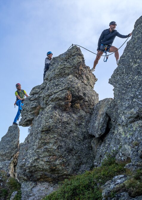 Three climbers secure themselves on a rugged rocky ridge at Schlossalm in Gastein under blue sky | © Balazs Kovacs