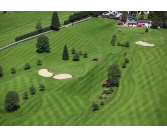 Aerial view of Golfclub Gastein with manicured fairways, sand bunkers, small huts and clubhouse in the background. | © Golf Club Gastein