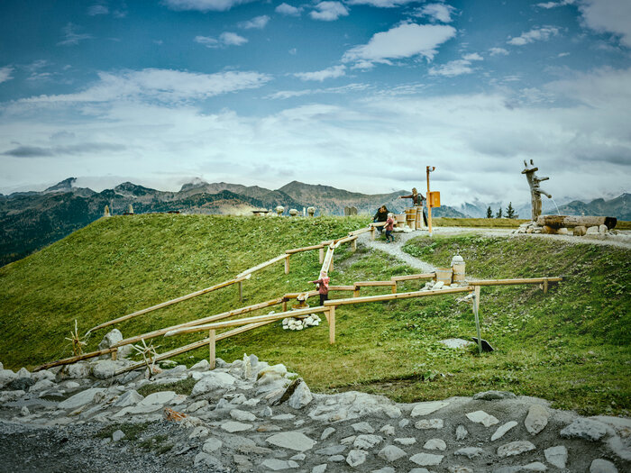 Children play at water stations on adventure trail in Grossarltal with wooden channels meadow and mountains | © Chris Rogl