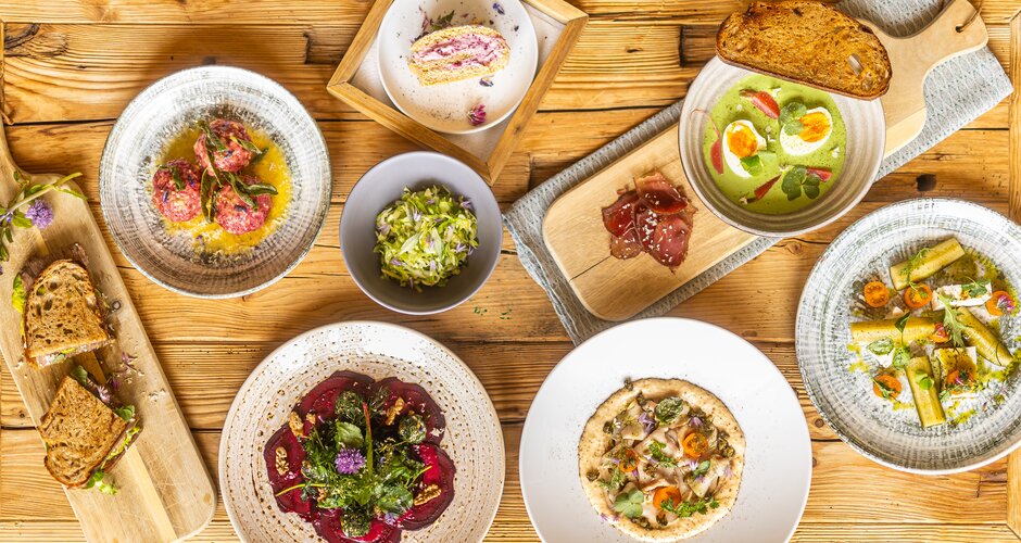 Several plated dishes with bread, soup, salad and dessert are arranged on a rustic wooden table. | © Hochkönig Tourismus GmbH