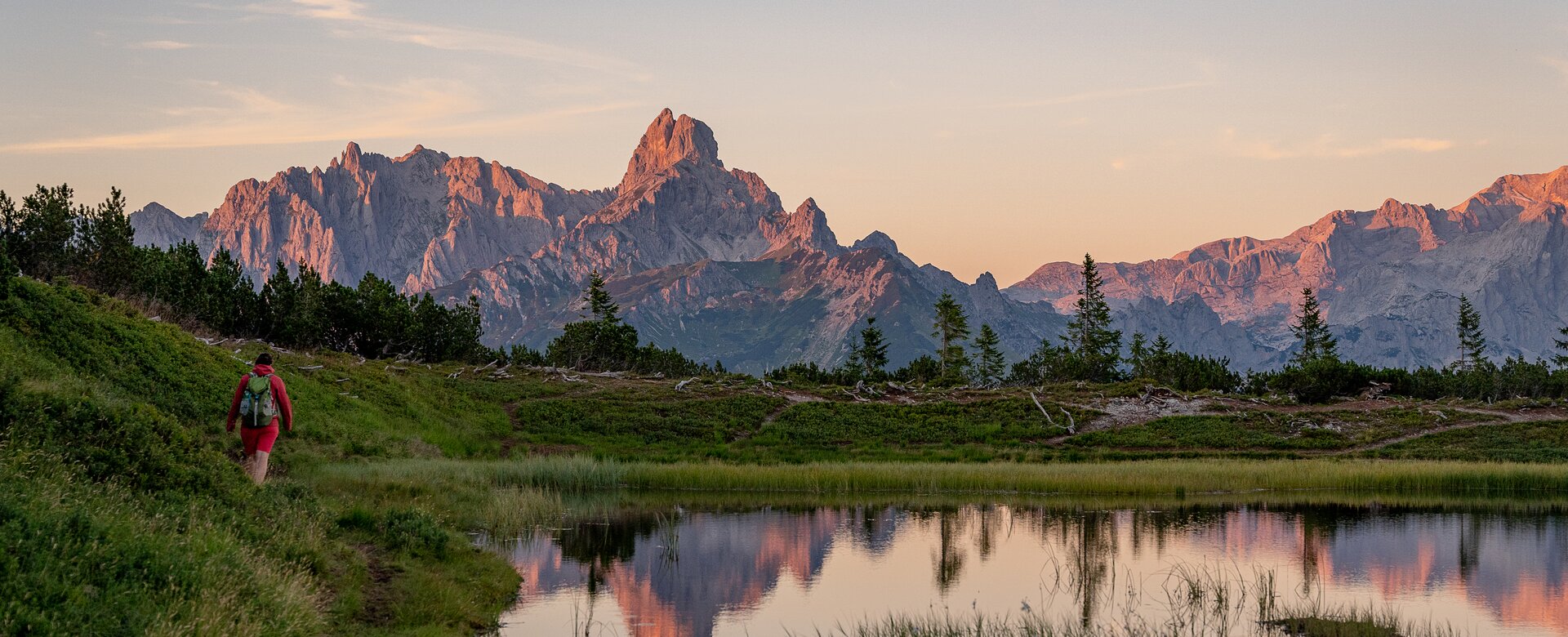 Hiker at Gerzkopf near Eben im Pongau with pond and Dachstein glowing in evening light | © TVB Eben - Nina Kraxner