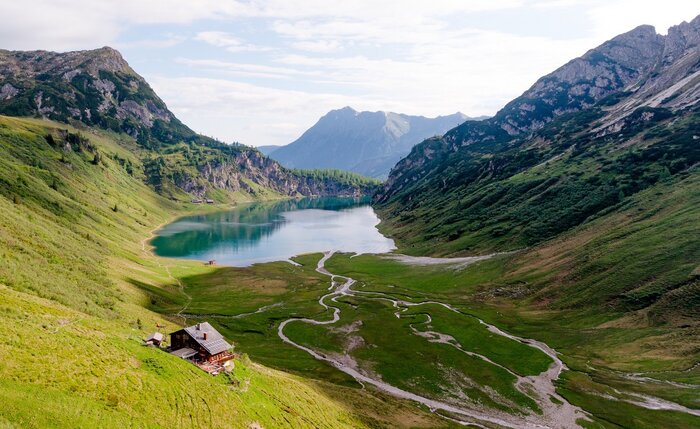 View of a clear alpine lake with hut, meadows and streams in a high valley surrounded by mountains | © Wagrain-Kleinarl Tourismus