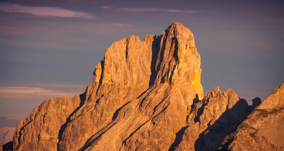 The Bischofsmütze mountain in the Dachstein range glows at sunset in warm golden light – rugged rock silhouette | © CoenWeesjes