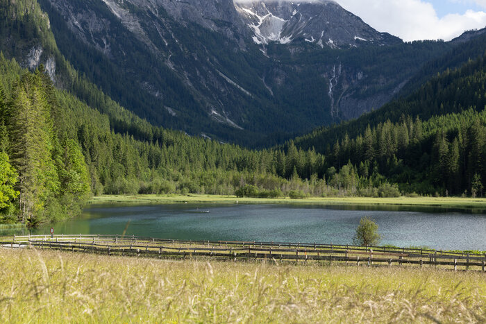 View of Lake Jägersee with clear water, meadows and dense forest framed by a striking mountain backdrop | © Wagrain-Kleinarl Tourismus/Robert Schabus