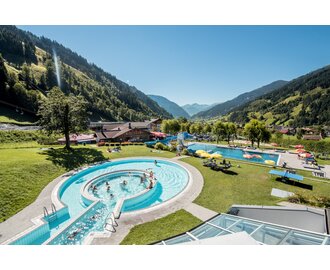 Outdoor pool at the Solarbad Dorfgastein with green mountain views and sunbathing lawn. | © Gasteinertal Tourismus GmbH