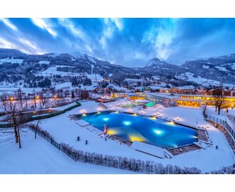 The Alpentherme Gastein with an illuminated outdoor pool in a snowy winter landscape. | © Gerhard Wolkersdorfer