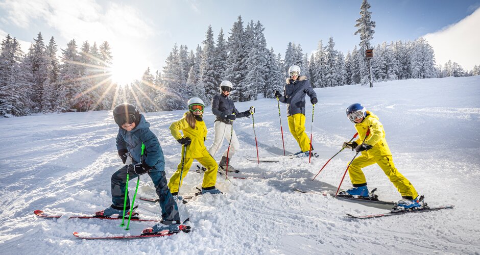 Family of five stands on skis in the snow and smiles