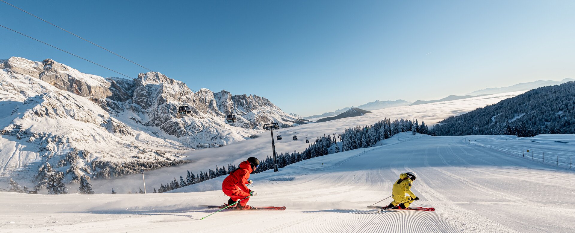 Two skiers at sunrise on freshly groomed slope in Mühlbach with alpine backdrop | © Hochkönig Tourismus GmbH