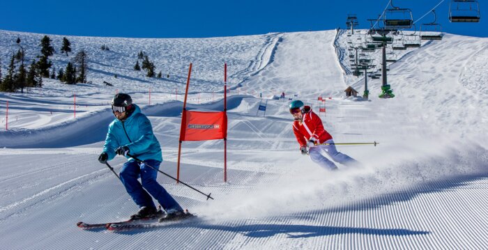 Skiers on a groomed race track with red gates at sunny Galsterberg. | © Ikarus.cc