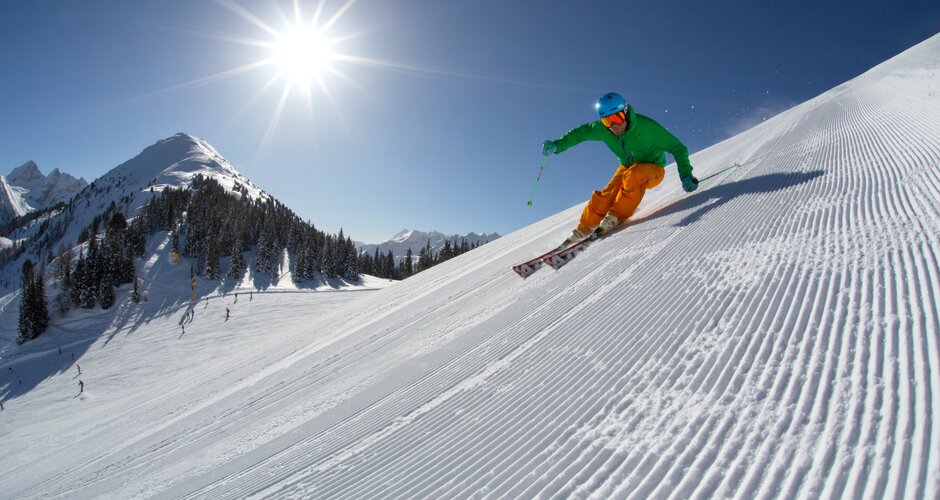 Skier in green helmet carving on a freshly groomed slope at Planai. | © Gregor Hartl