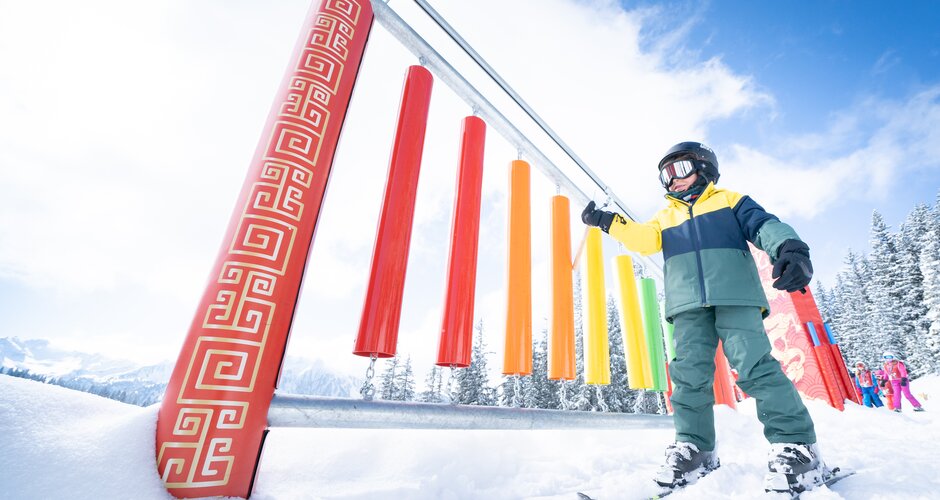 Child skis past coloured bars and touches them with a stick | © Josh Absenger
