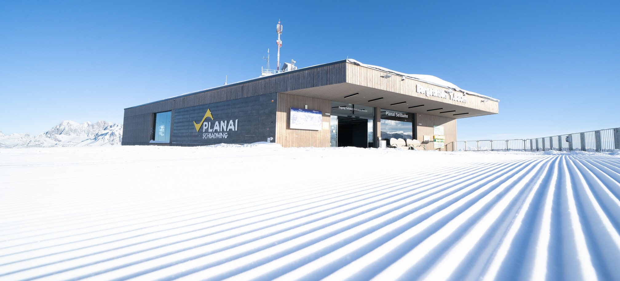 Planai mountain station with smooth, freshly groomed ski slope and alpine backdrop. | © Josh Absenger