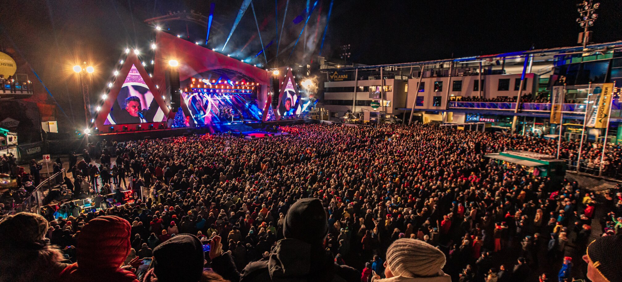 Large crowd at a night concert with light show and stage at Planai. | © Vanray