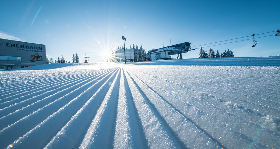 Freshly groomed ski slope with a view of the mountain lift stations from below