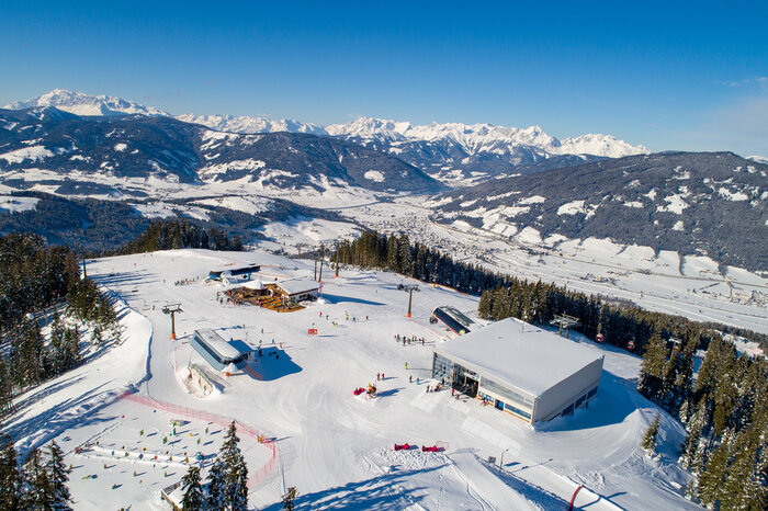 Plateau of a ski resort from above with three mountain stations and several skiers